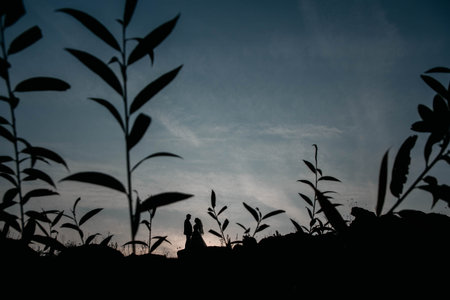Silhouettes of a young couple lovers at sunset on dramatic sky background. Place for text or advertising.の写真素材