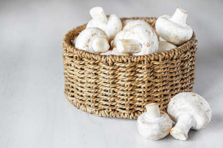 Mushrooms champignons in paper bag on a white wooden table. Place for text or advertising.の写真素材