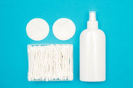 Cotton pads, plastic bottle and cotton buds on blue background. Spa concept. Cotton Cosmetic Makeup...