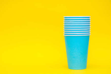 Blue paper cup with drinking colored plastic straws on yellow background. Set for party. Minimalist Style. Copy, empty space for text.の写真素材