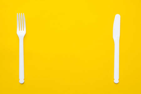 White plastic spoon on blue and yellow background. Top view. Copy, empty space for text.の写真素材