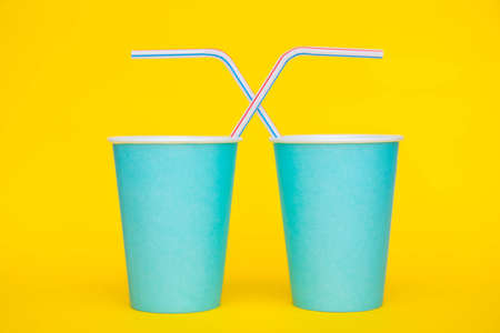 Pattern from blue paper disposable cups on yellow background. Set for party. Top view. Minimalist Style. Copy, empty space for text.の写真素材