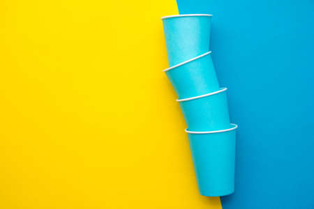 Pattern from blue paper disposable cups on yellow background. Set for party. Top view. Minimalist Style. Copy, empty space for text.の写真素材