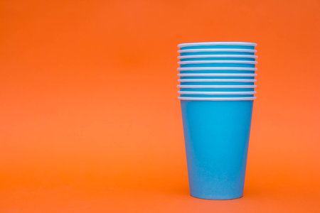 Many blue paper cups on orange background. Set for party. Copy, empty space for text.の写真素材