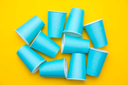Pyramid of blue paper disposable cups on yellow background. Set for party. Copy, empty space for text.の写真素材
