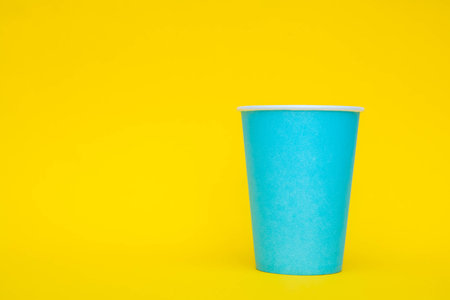 Pyramid of blue paper disposable cups on yellow background. Set for party. Copy, empty space for text.の写真素材