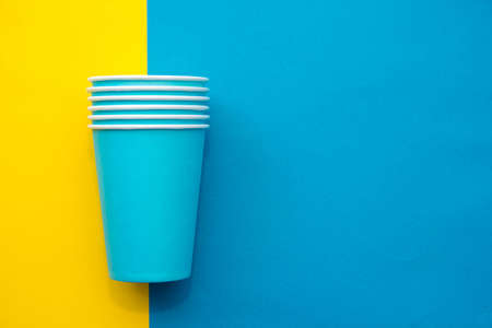 Pyramid of blue paper disposable cups on yellow background. Set for party. Copy, empty space for text.の写真素材