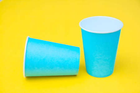 Pattern from blue paper disposable cups on yellow background. Set for party. Top view. Minimalist Style. Copy, empty space for text.の写真素材