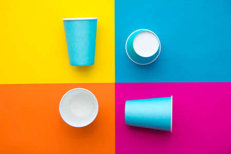 Blue paper cups with drinking colored plastic straws on beautiful multicolored background. Set for party. Top view. Minimalist Style. Copy, empty space for text.の写真素材