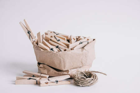 Wooden clothespins in paper bag with rope on white background. Place for your text.の写真素材