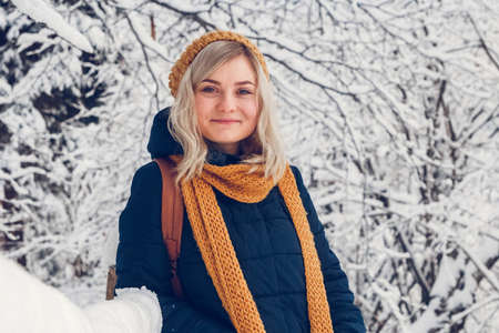 Beautiful young girl in a winter forest. Winter portrait of girl dressed in cap and scarf. Place for text or advertising.の写真素材