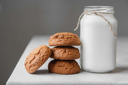 Milk in a glass jar and oatmeal cookies on a white table background. Copy, empty space for text.の写真素材