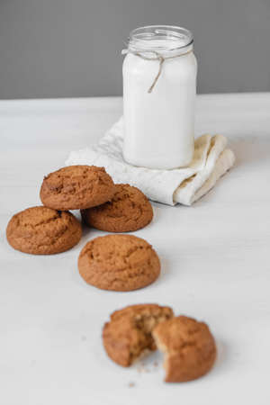 Milk in a glass jar and oatmeal cookies on a white table background. Copy, empty space for text.の写真素材