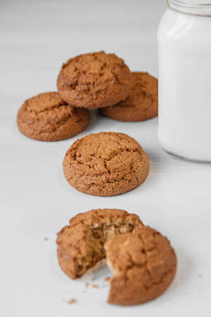 Milk in a glass jar and oatmeal cookies on a white table background. Copy, empty space for text.の写真素材