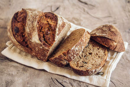 Brown fresh bread with seeds on old wood background. Top view, copy space.の写真素材