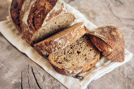 Brown fresh bread with seeds on old wood background. Top view, copy space.の写真素材