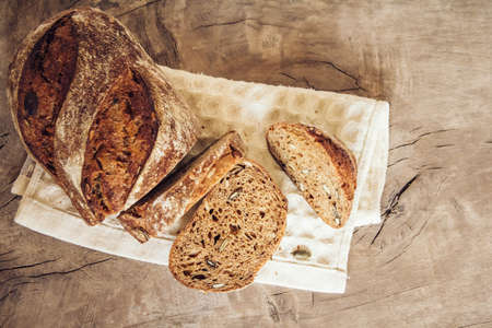 Brown fresh bread with seeds on old wood background. Top view, copy space.の写真素材