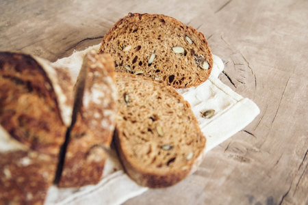 Brown fresh bread with seeds on old wood background. Top view, copy space.の写真素材