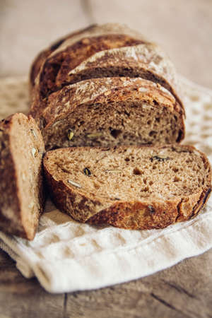 Brown fresh bread with seeds on old wood background. Top view, copy space.の写真素材