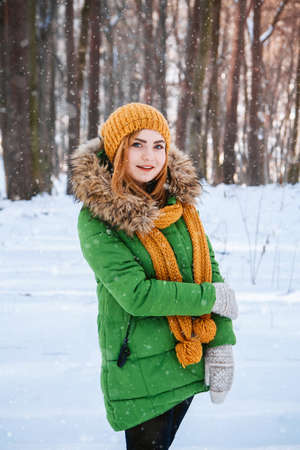Beautiful young girl in a winter forest. Winter portrait of women dressed in mittens and scarf. Place for text or advertising.の写真素材