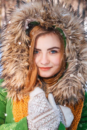 Beautiful young girl in a winter forest. Winter portrait of women dressed in mittens and scarf. Place for text or advertising.の写真素材
