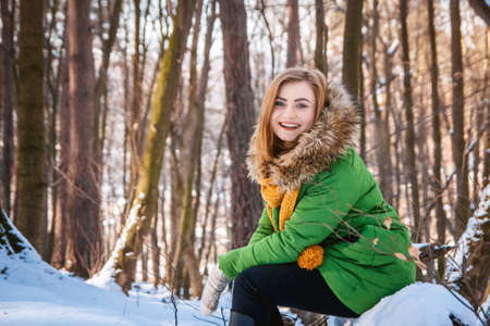 Beautiful young girl in a winter forest. Winter portrait of women dressed in mittens and scarf. Place for text or advertising.の写真素材