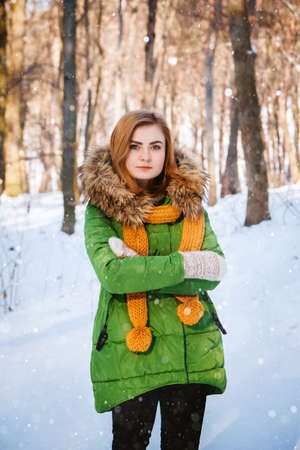 Beautiful young girl in a winter forest. Winter portrait of women dressed in mittens and scarf. Place for text or advertising.の写真素材