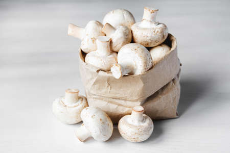 Mushrooms champignons lie in a row on a white table on a dark background. Place for text or advertising.の写真素材