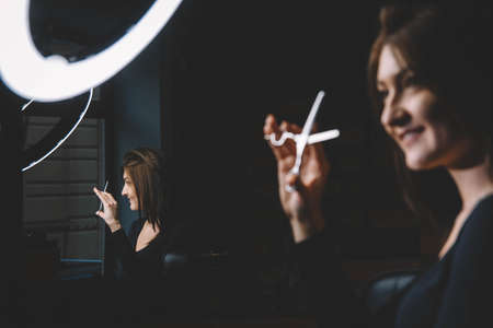 Beautiful woman hairdresser with scissors in hand. Barbershop advertising concept. Place for text or advertising.の写真素材