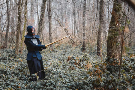 Man practicing kendo with shinai bamboo sword on forest background. Place for text or advertising.の写真素材