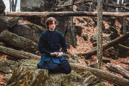 Man practicing kendo with shinai bamboo sword on forest background. Place for text or advertising.の写真素材