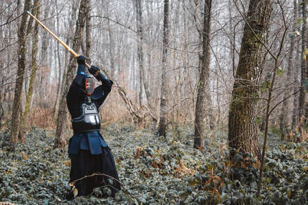 Man practicing kendo with shinai bamboo sword on forest background. Place for text or advertising.の写真素材