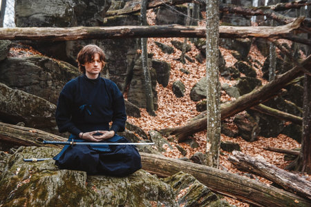 Man practicing kendo with shinai bamboo sword on forest background. Place for text or advertising.の写真素材