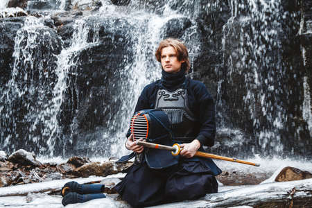 Portrait of man kendo fighter on forest background. Place for text or advertising.の写真素材
