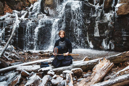 Portrait of man kendo fighter on forest background. Place for text or advertising.の写真素材