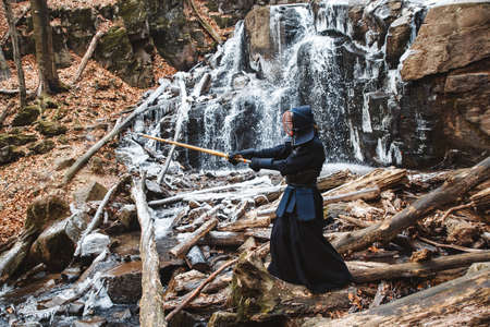Portrait of man kendo fighter on forest background. Place for text or advertising.の写真素材