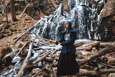 Portrait of man kendo fighter on forest background. Place for text or advertising.の写真素材