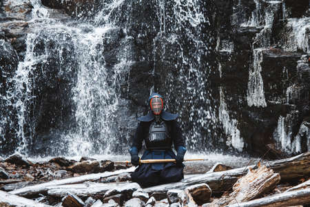 Portrait of man kendo fighter on forest background. Place for text or advertising.の写真素材