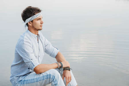 Man sitting on wooden bridge and looks at the water reflex of blue sky. Concept of freedom relaxation. Place for text or advertising.の写真素材