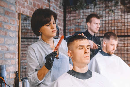 Hairdressers cut their clients in barbershop. Advertising and barber shop concept.の写真素材