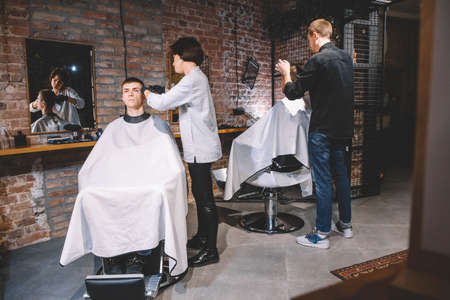 Hairdressers cut their clients in barbershop. Advertising and barber shop concept.の写真素材