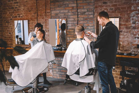 Hairdressers cut their clients in barbershop. Advertising and barber shop concept.の写真素材