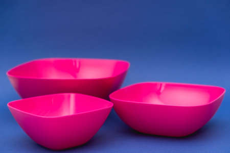 Set of pink plates on blue background. Plastic utensils for the kitchen. Copy, empty space for text.の写真素材