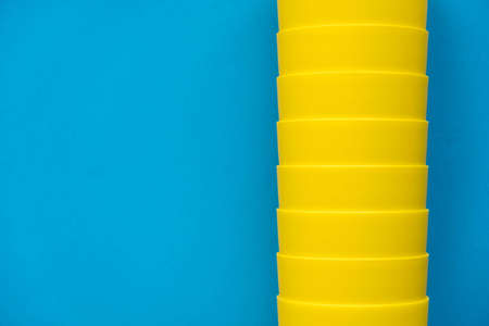 Yellow plastic building blocks on blue and yellow background. Pieces and elements of constructor. Parts of bright small spare parts for toys. Top view. Copy, empty space for text.の写真素材
