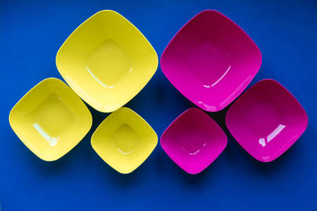 Yellow plastic building blocks on blue and yellow background. Pieces and elements of constructor. Parts of bright small spare parts for toys. Top view. Copy, empty space for text.の写真素材