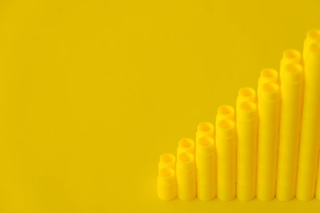 Yellow plastic building blocks on blue and yellow background. Pieces and elements of constructor. Parts of bright small spare parts for toys. Top view. Copy, empty space for text.の写真素材