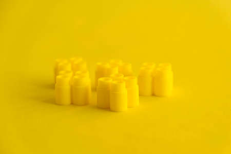 Yellow plastic building blocks on yellow background. Background of plastic details building blocks. Parts of bright small spare parts for toys. Top view. Copy, empty space for text.の写真素材
