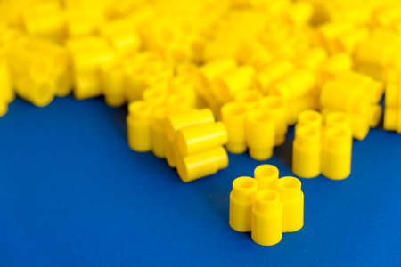 Yellow plastic building blocks on yellow background. Background of plastic details building blocks. Parts of bright small spare parts for toys. Top view. Copy, empty space for text.の写真素材