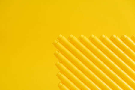 Yellow plastic building blocks on yellow background. Background of plastic details building blocks. Parts of bright small spare parts for toys. Top view. Copy, empty space for text.の写真素材