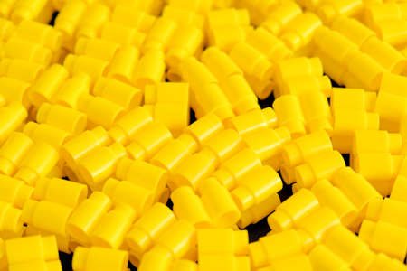 Yellow plastic building blocks on yellow background. Background of plastic details building blocks. Parts of bright small spare parts for toys. Top view. Copy, empty space for text.の写真素材